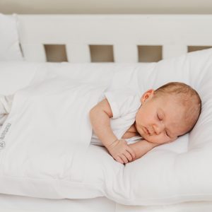 a baby lying in nurtureone nesting cushion