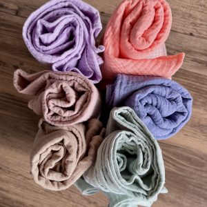 a pile of muslin baby blankets in various colours