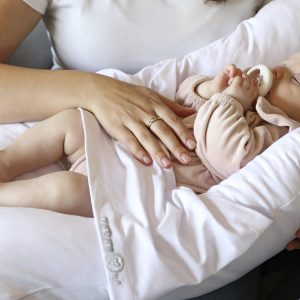 A nurtureone nesting cushion with baby lying in it on its mothers lap